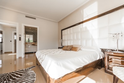 棕色木制床架，白色床罩，旁边是棕色木制床头柜